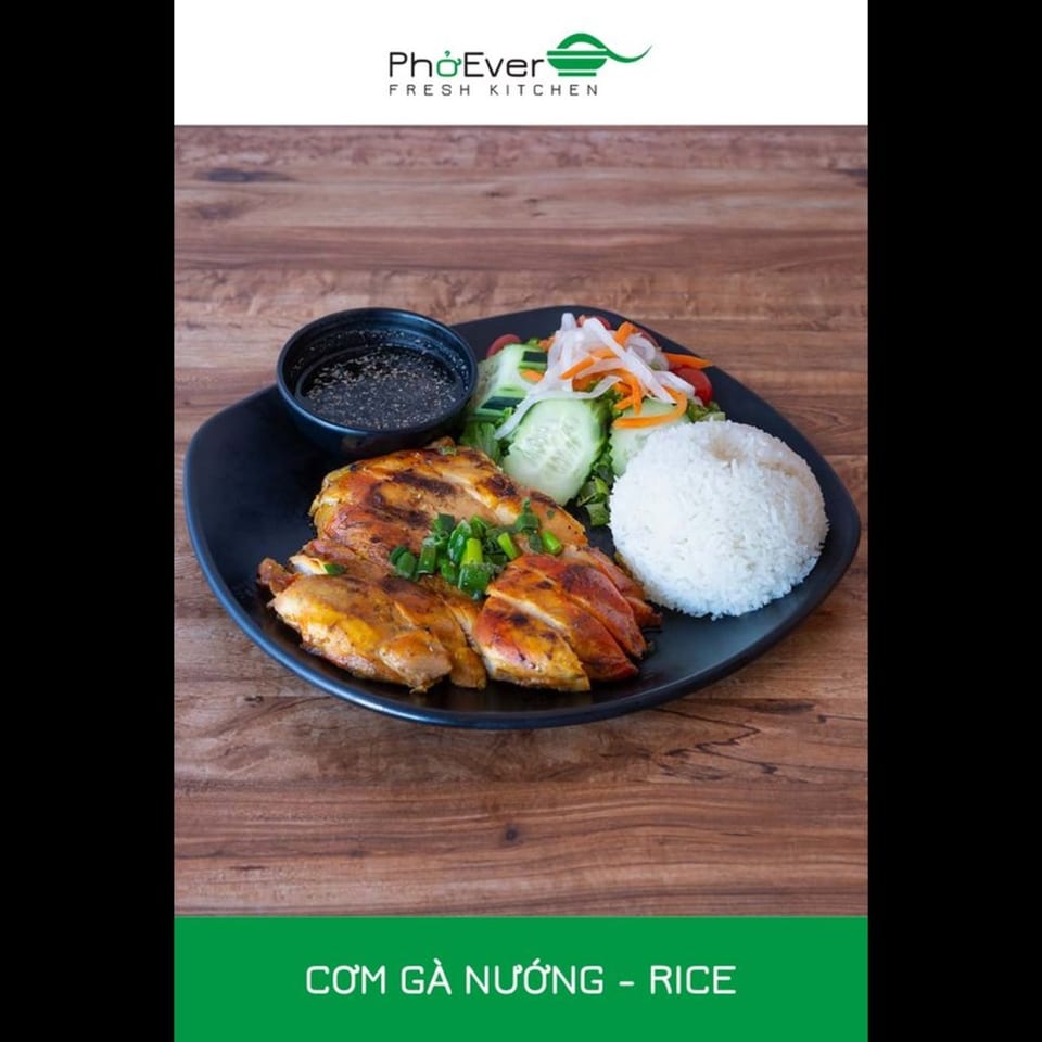 Grilled chicken with rice, salad, and dipping sauce on a black plate.