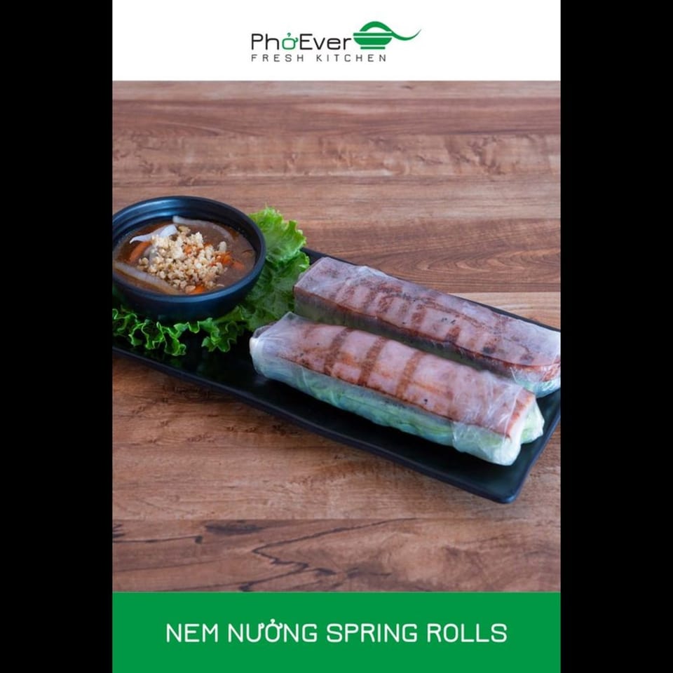 Two Nem Nuong Spring Rolls with a side of dipping sauce on a black plate.