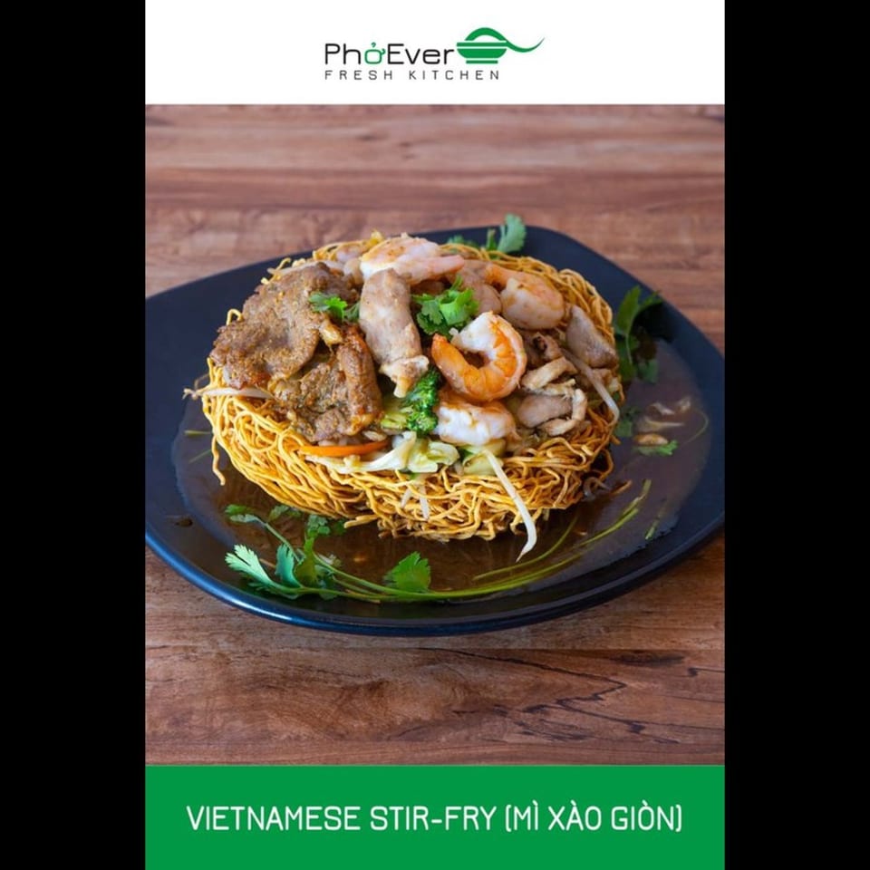A Vietnamese stir-fry with crispy noodles, beef, shrimp, and vegetables in a dark sauce.